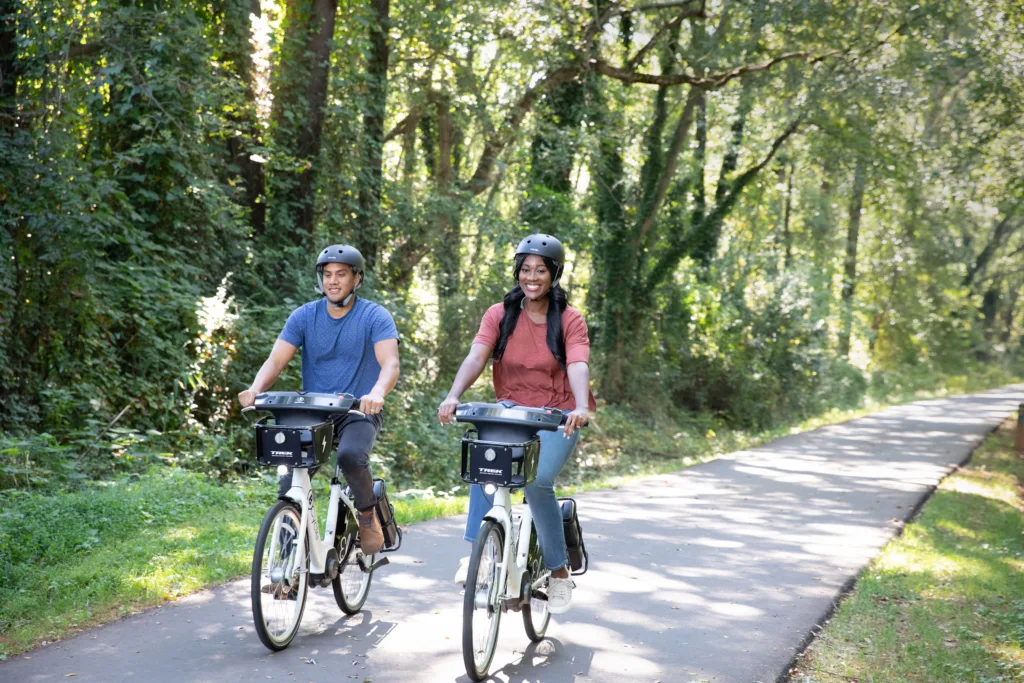 photo of a man and woman riding bike share bicycles on a paved path